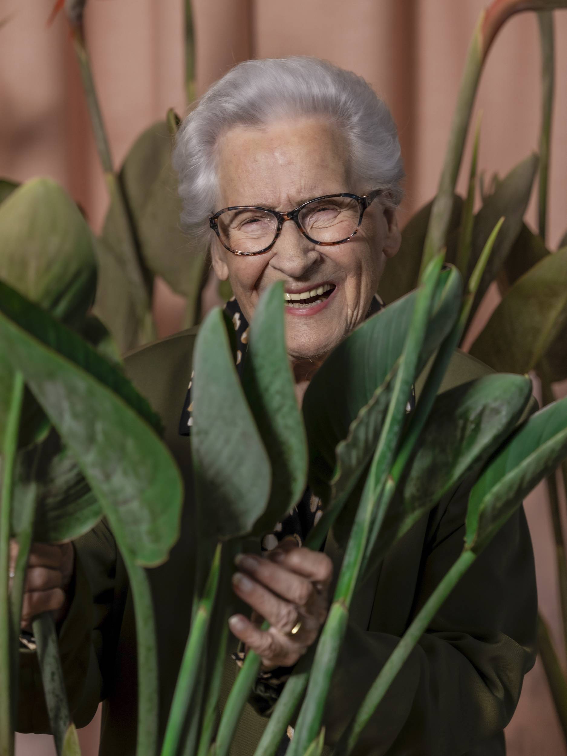 lachende oudere vrouw, oma, omringd door planten