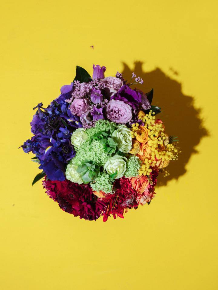 Bovenaanzicht van kleurrijk boeket bloemen tegen felgele achtergrond.